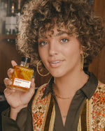 person holding a bottle of strongwater orange bitters in a bar setting